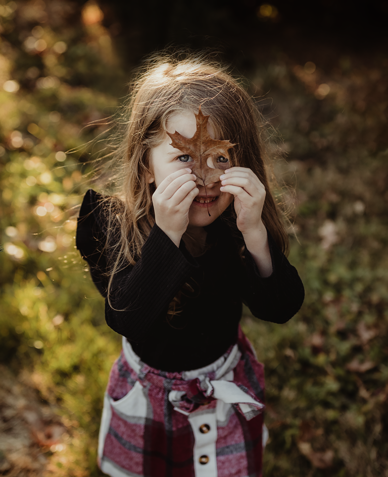 a small girl playing with a leaf
