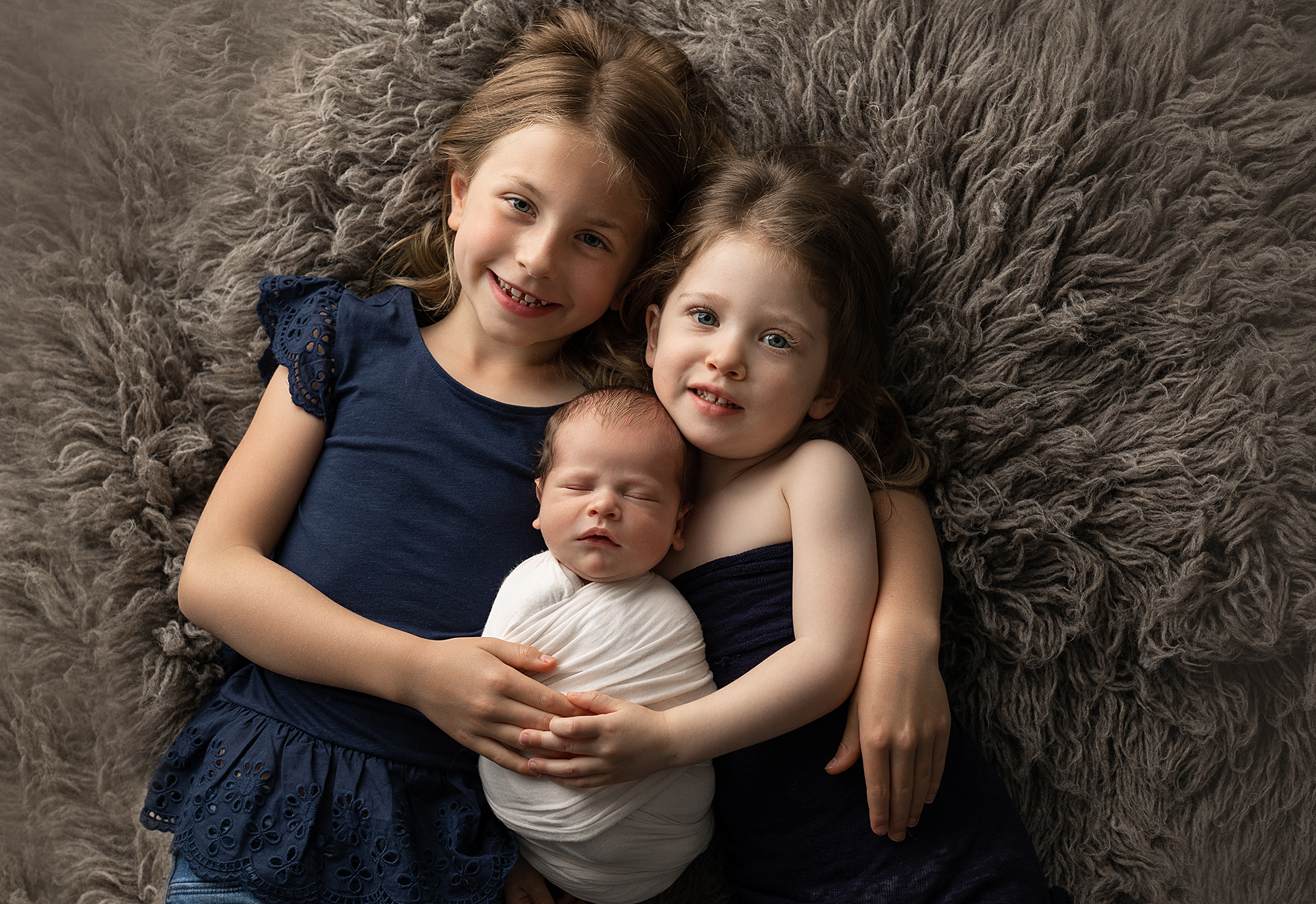 Cute Sisters Posing With Their Little Baby Sibling