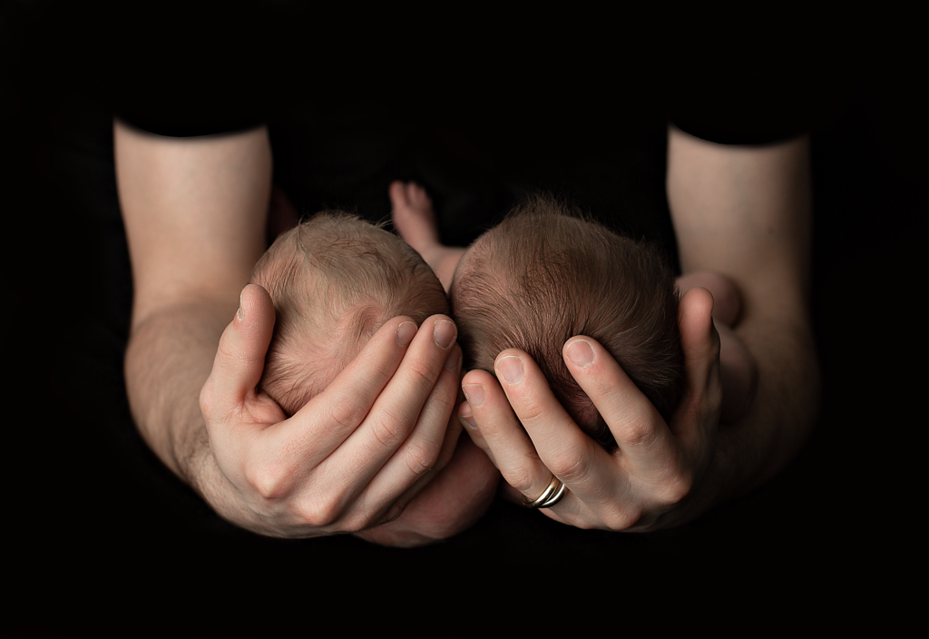Dad holding twin baby boys in his hands