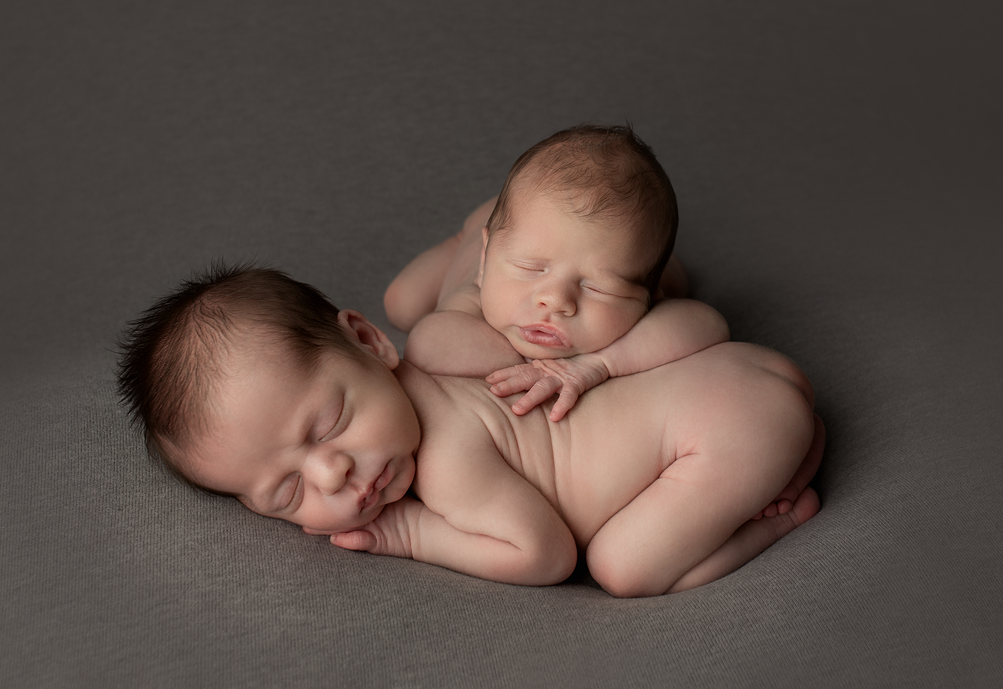 newborn twin boys snuggled up with one another
