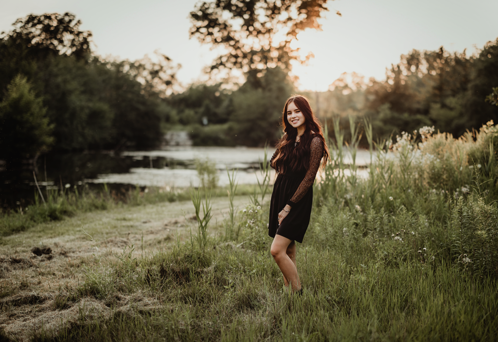 High school senior posing by the pond during a golden hour senior photography session at Rolling Knolls Forest Preserve in Elgin, Illinois.