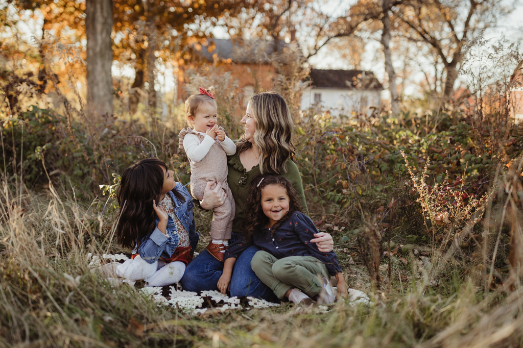 Mother and her three daughters enjoying a candid fall family photography session at Leroy Oaks Forest Preserve in St. Charles, Illinois.