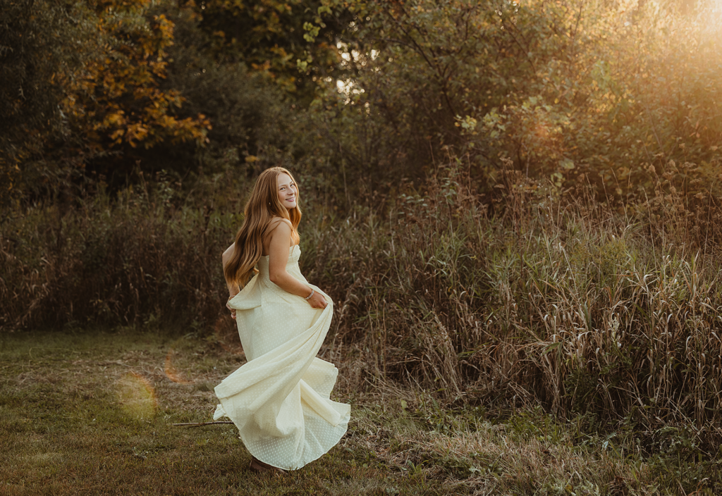 Central High School senior in a flowing cream dress walking through Burnidge Forest Preserve in Elgin, Illinois.