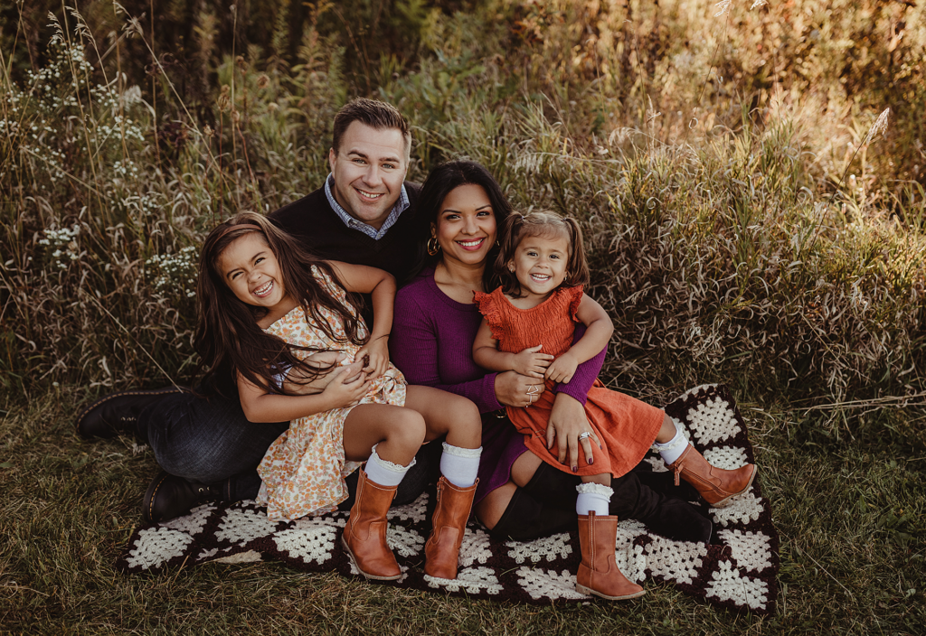 Family of four smiling together during a fall family photography session at Burnidge Forest Preserve in Elgin, Illinois.