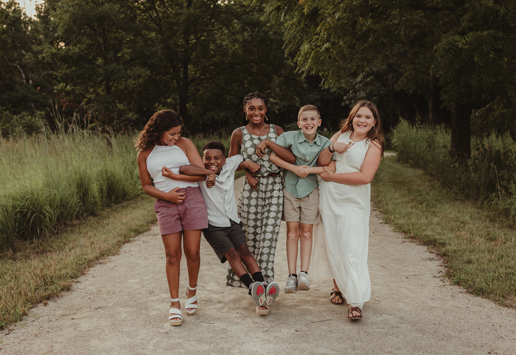Five children walking arm-in-arm and laughing during an outdoor family photography session at Cuba Marsh Forest Preserve in Lake Zurich, Illinois.