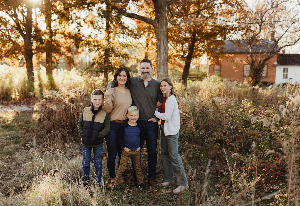 Family of five posing together among fall foliage at Leroy Oakes Forest Preserve in St. Charles, Illinois.
