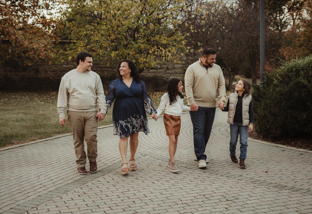 Family walking together on a brick pathway surrounded by autumn trees in Downtown Batavia