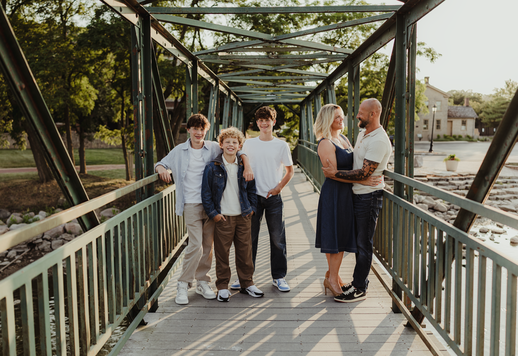 Family standing together on the pedestrian bridge during a portrait session in downtown St. Charles, Illinois.