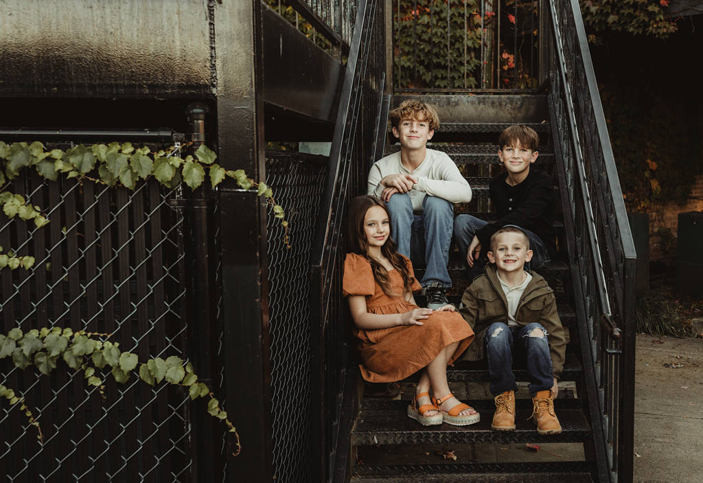Four siblings sitting together on a staircase in downtown West Dundee, Illinois