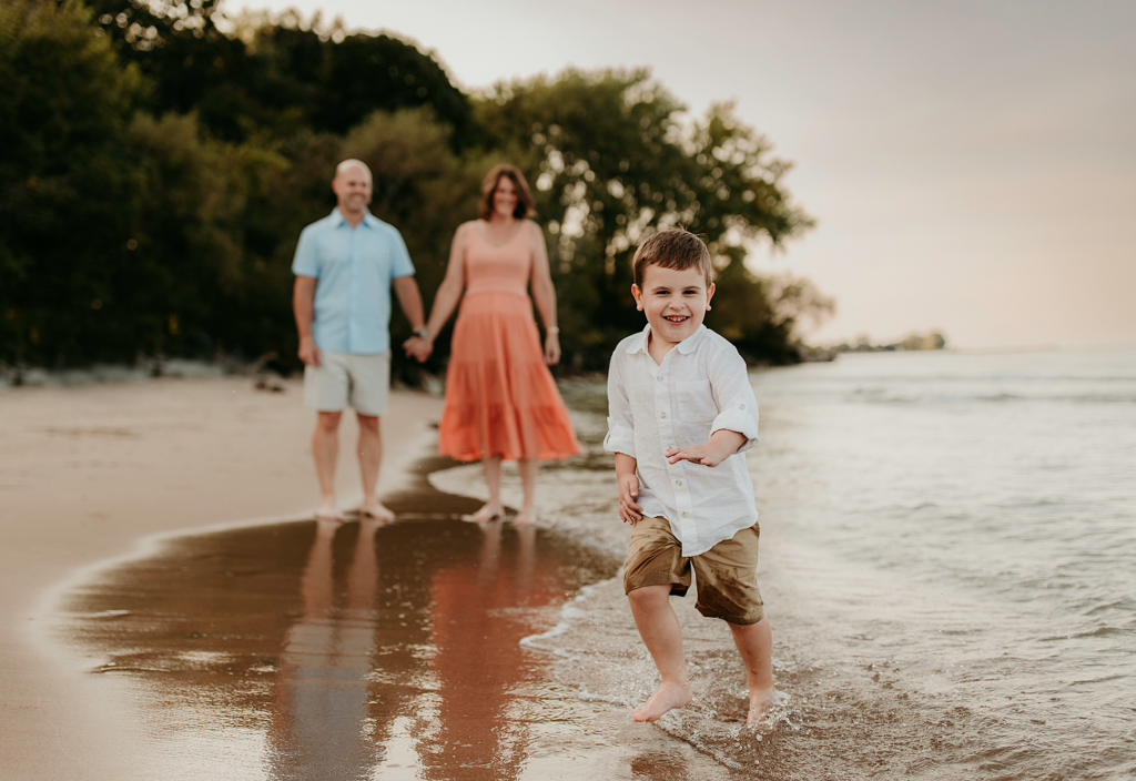 Young boy running barefoot through the shallow water at Lighthouse Beach in Evanston, Illinois.