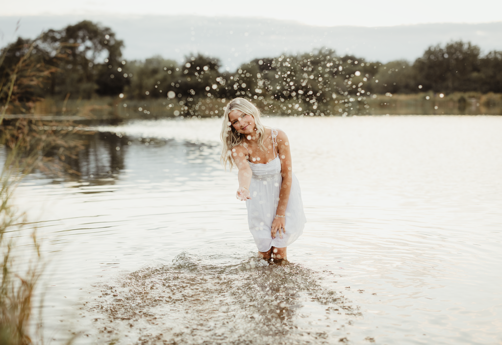 Central High School senior splashing water while standing in Mallard Lake during a summer portrait session in Hanover Park, Illinois.