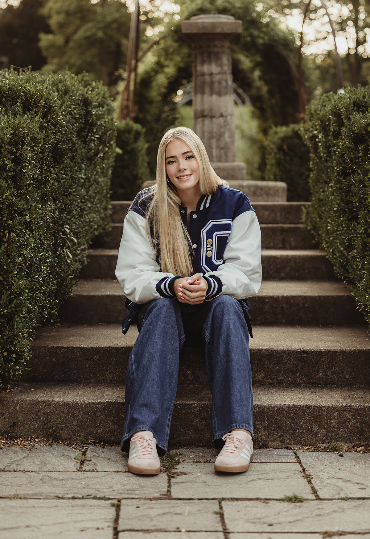 Central High School senior sitting on garden steps in her varsity letterman jacket at Fabyan Forest Preserve