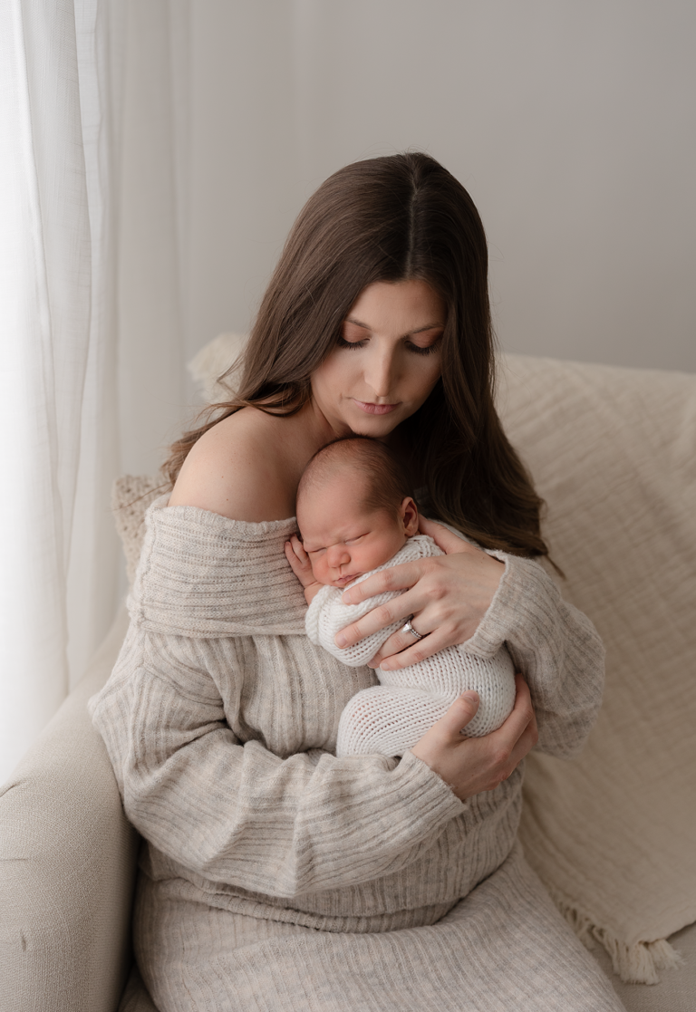 Mother holding her sleeping newborn during a neutral studio newborn session in Elgin, Illinois