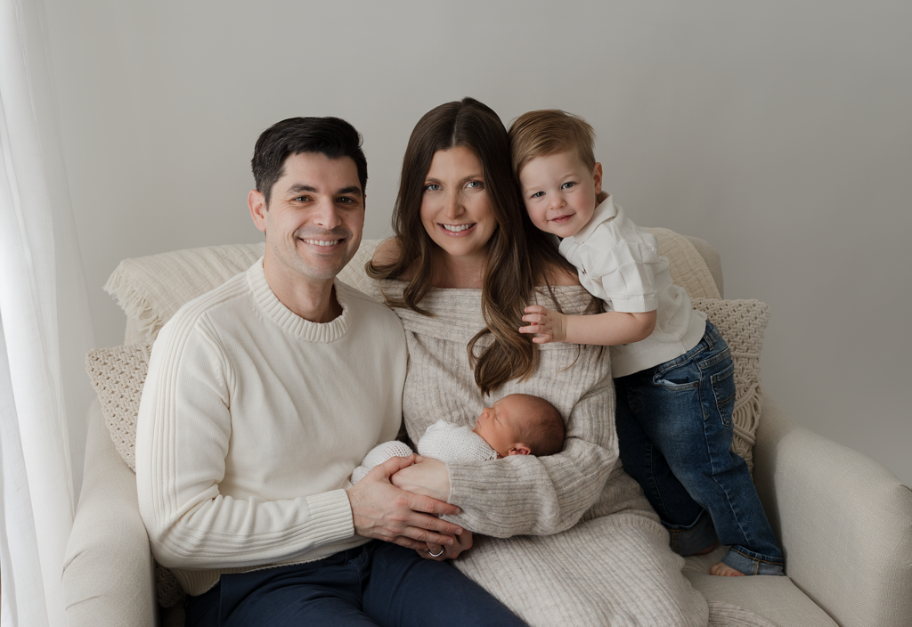 Family of four with parents, toddler and newborn during a studio newborn photography session