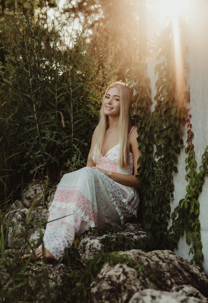 Central High School senior in a floral dress sitting beside ivy at Fabyan Forest Preserve during golden hour