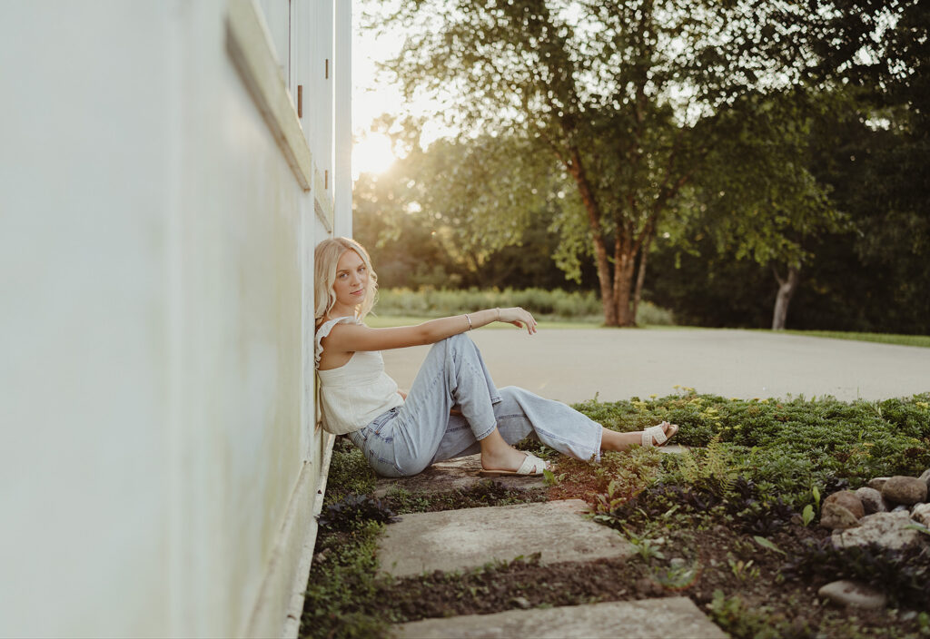 Hampshire High School senior sitting on a stone path in a white top and jeans at LeRoy Oakes Forest Preserve