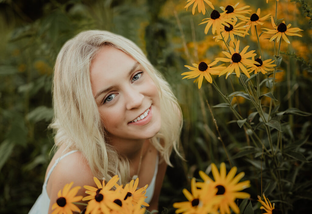 Close-up portrait of a blonde Hampshire High School senior surrounded by yellow wildflowers