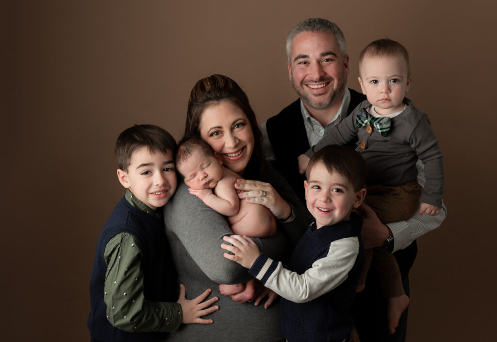 Parents and three older children gathered around their newborn during a family newborn portrait