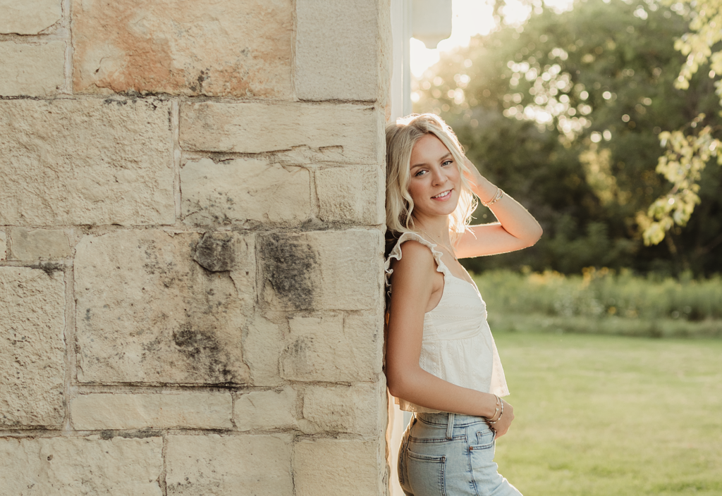 Hampshire High School senior leaning against a stone building during her senior photo session at Leroy Oakes Forest Preserve