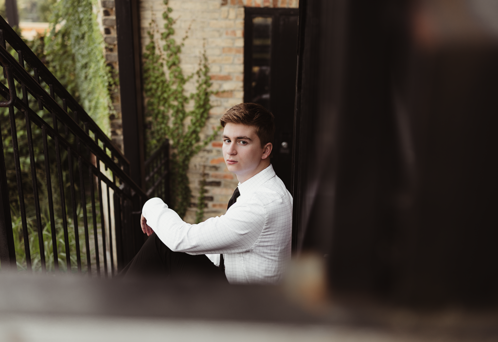 Huntley High school senior guy posing on an outdoor staircase for an urban senior portrait in the Chicago suburbs