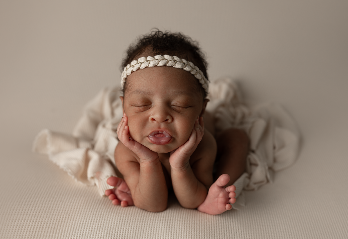 Newborn baby girl posed on a cream blanket during a studio newborn photography session in Elgin, Illinois