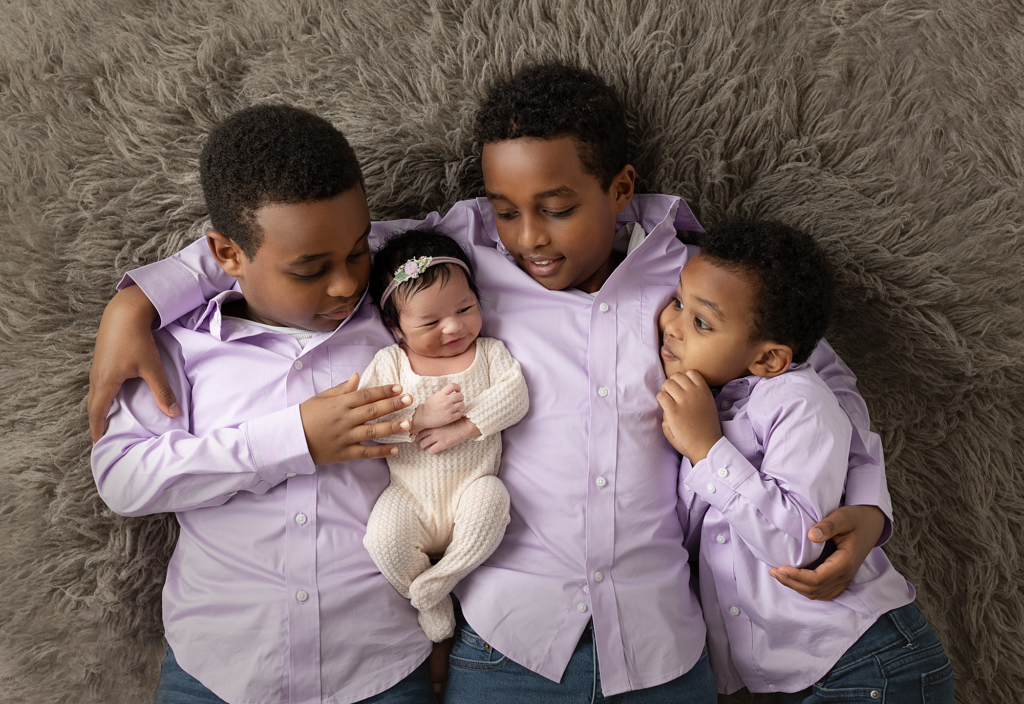 Three brothers gathered around their newborn sister during an Elgin newborn photography session