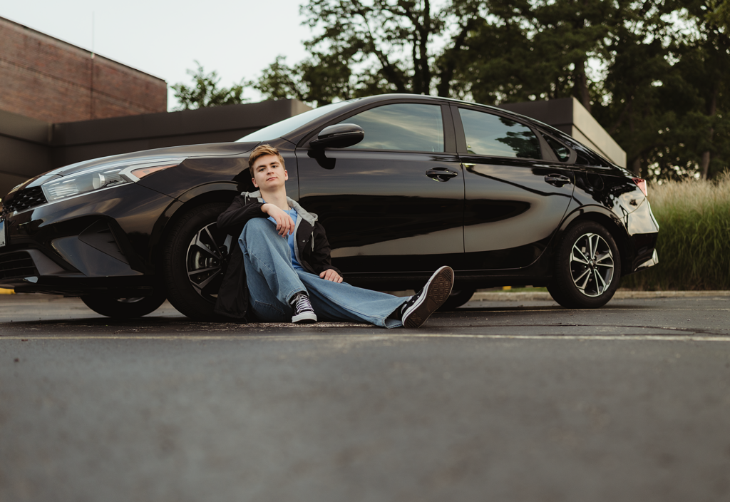 Huntley High school senior guy posing with his black car during an urban senior photography session in downtown West Dundee