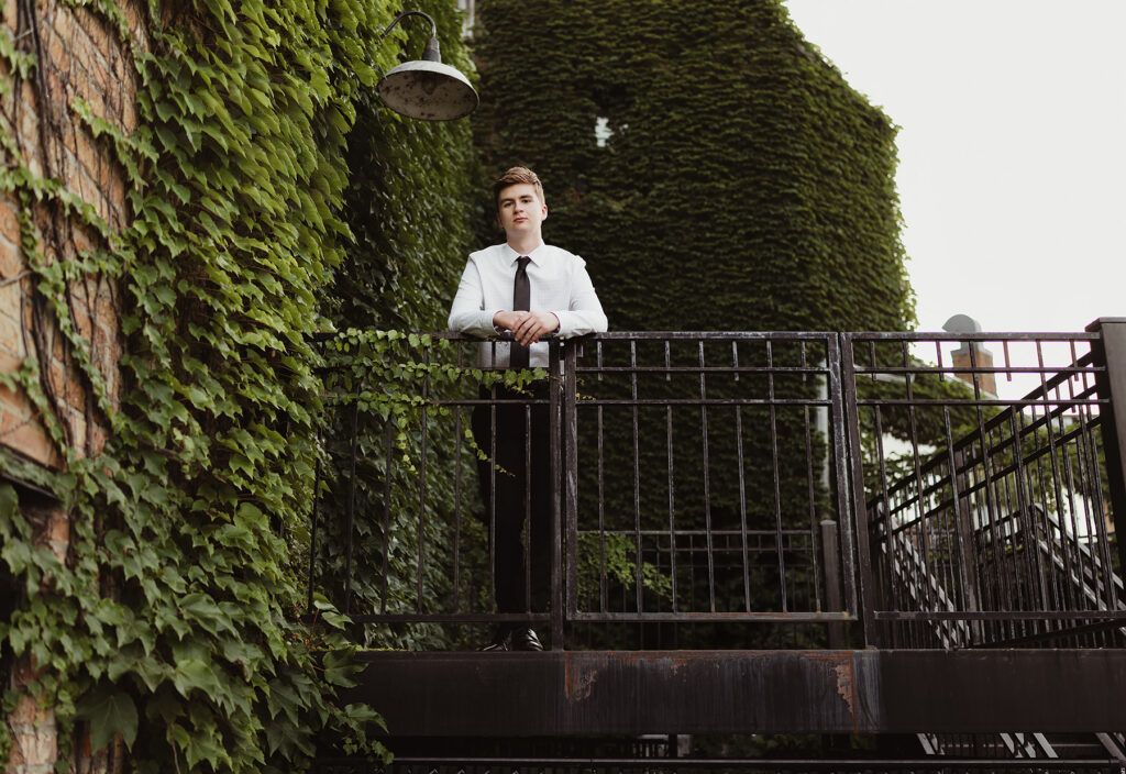 Huntley High school senior guy posing on an ivy-covered urban walkway in downtown West Dundee, Illinois