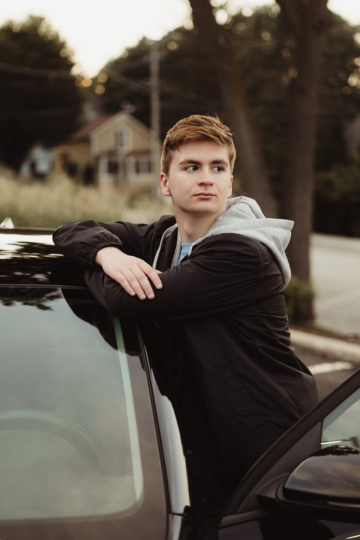 High school senior leaning against his car during an outdoor senior portrait session in West Dundee