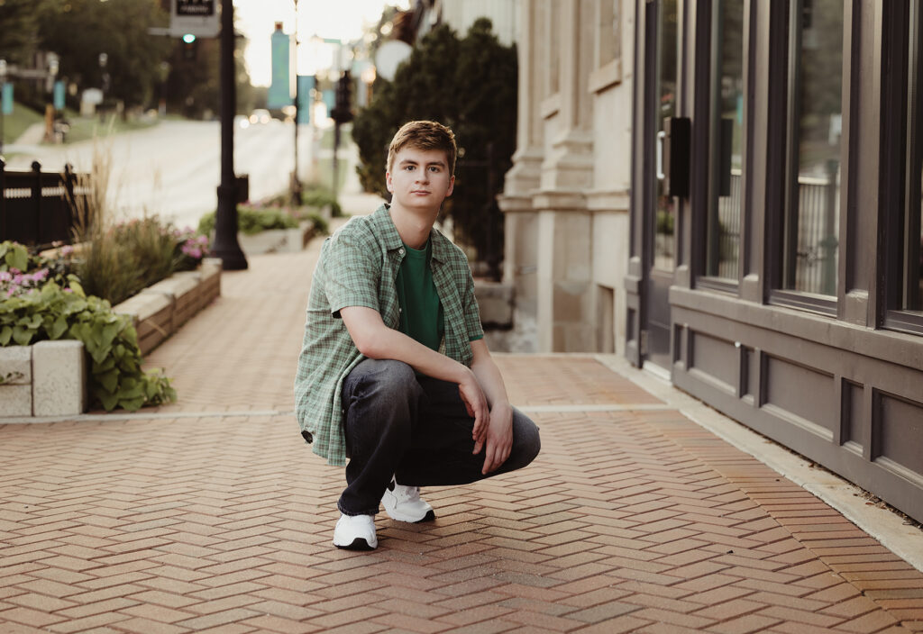 Huntley High school senior guy posing on a brick sidewalk in downtown West Dundee, Illinois