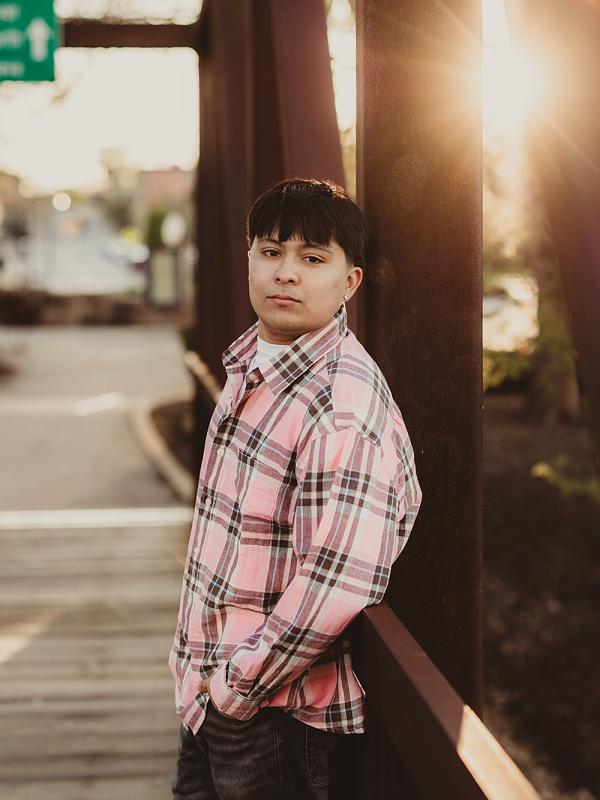 South Elgin High School senior leaning against a bridge railing at sunset in Downtown Batavia