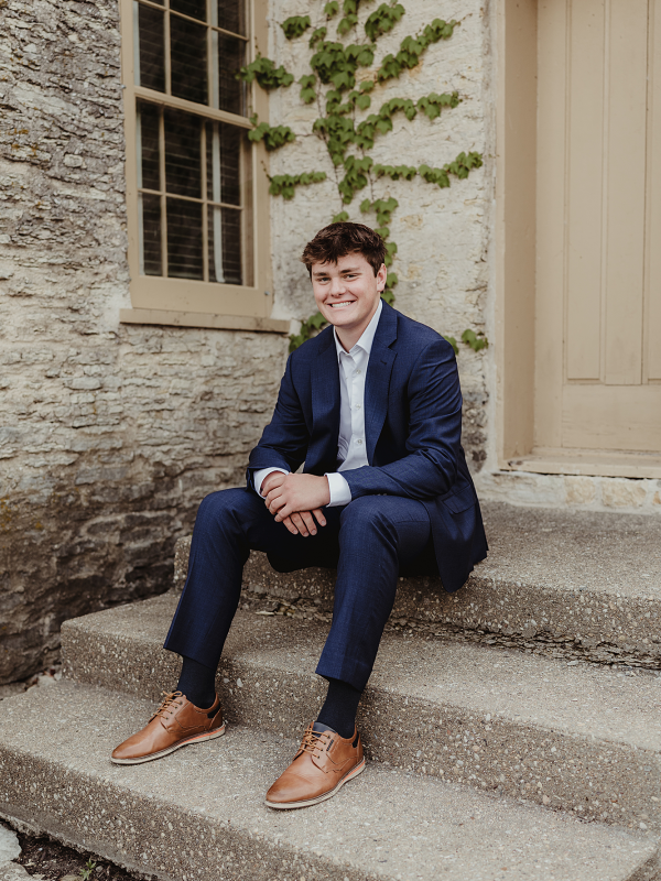 Central High School senior sitting on stone steps outside a historic building in downtown St. Charles, Illinois.