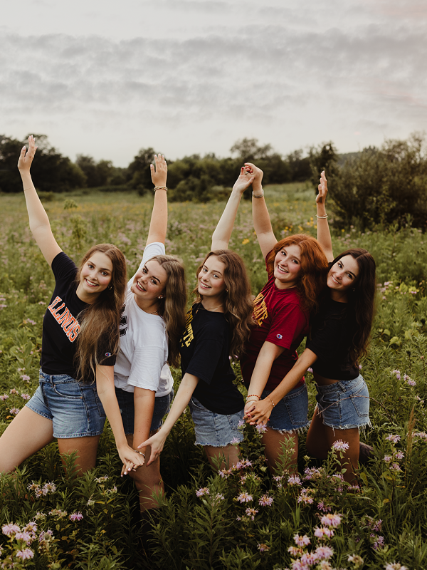 Five high school senior best friends posing together in a wildflower field during a senior photo session in Elgin, Illinois.